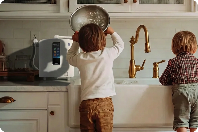 Two children at a kitchen sink beside a PeakSpring countertop dispenser