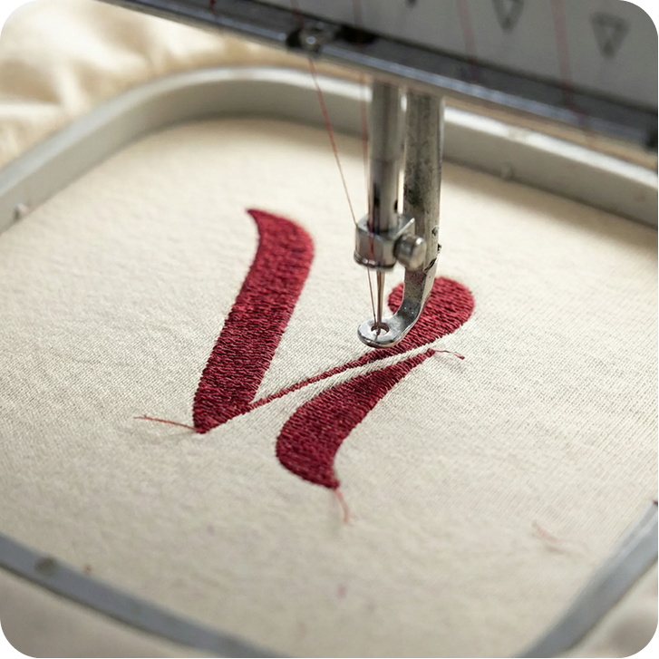 Viva Fashion V monogram being embroidered in red thread onto cream fabric